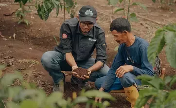 Un homme montre de la terre dans ses mains à un autre homme