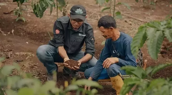 Un homme montre de la terre dans ses mains à un autre 