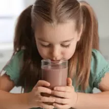 La fille boit une boisson dans une tasse transparente