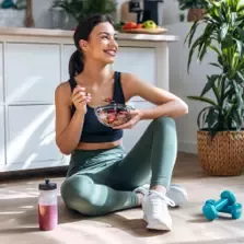Une jeune fille prend le petit déjeuner par terre après l’entraînement
