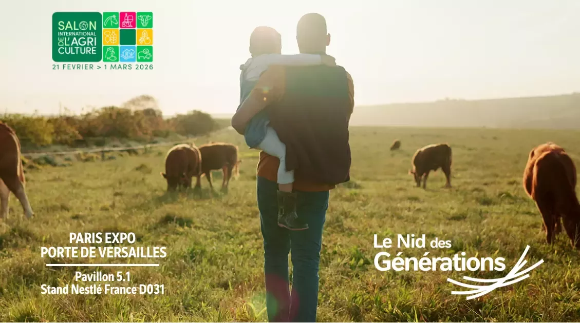 agriculteur de dos dans un champs avec sa fille sur les épaules face à un troupeau de vache