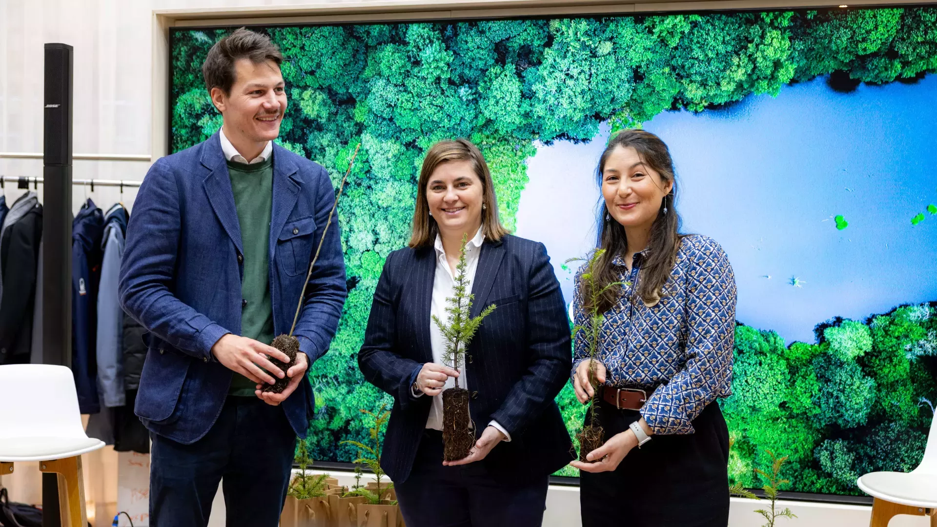 des employés Nestlé et d’Ecotree tiennent des pousses à planter devant un écran