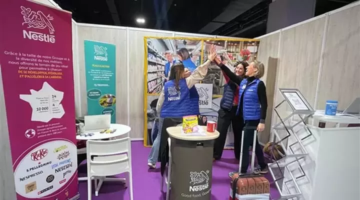 Stand Nestlé avec membres d’équipe levant les mains.